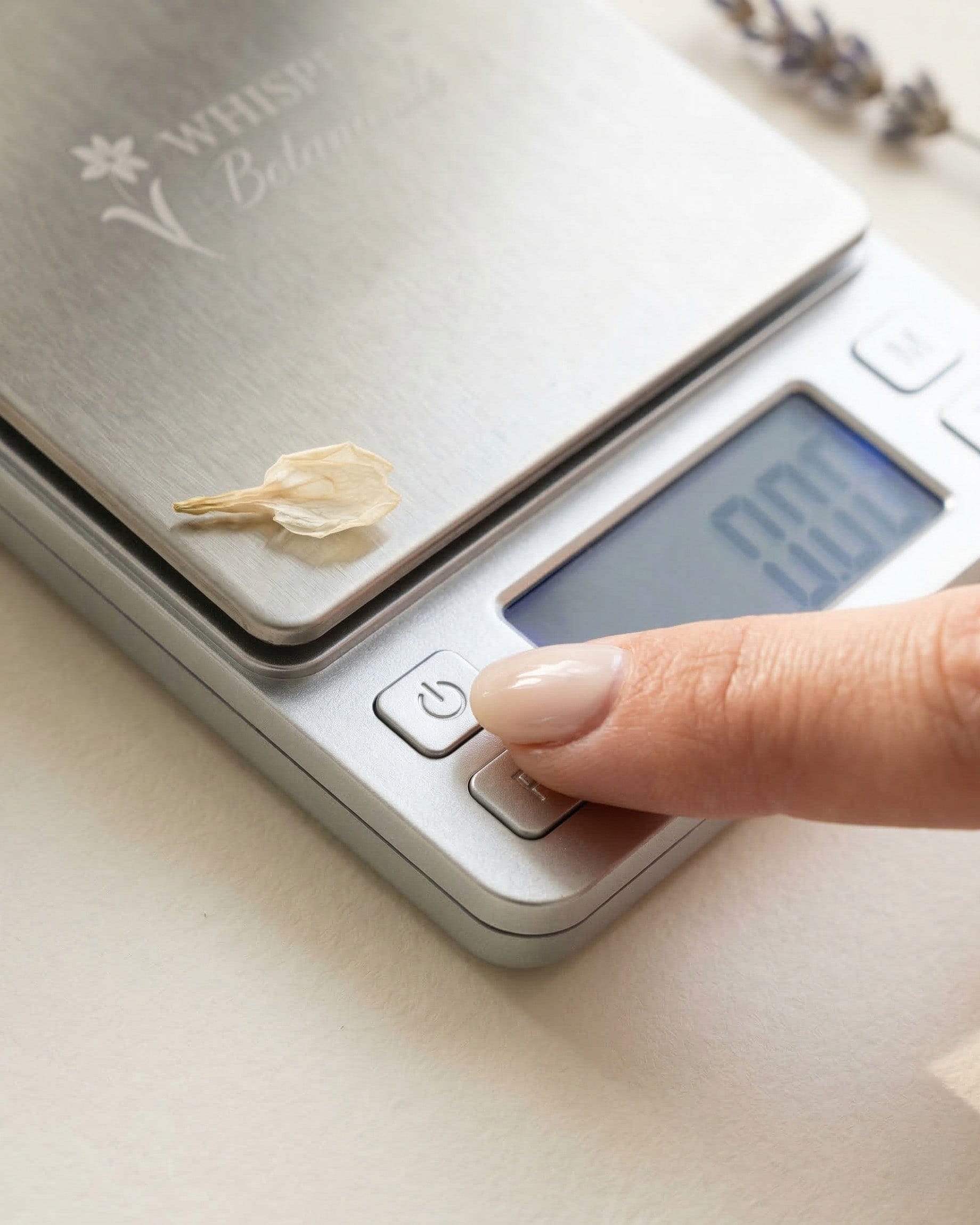 Digital kitchen scale with a flower petal on a light surface.